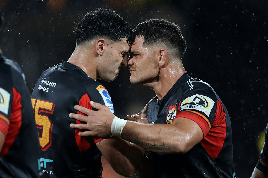two men with shirt hair and wearing rugby uniforms press noses