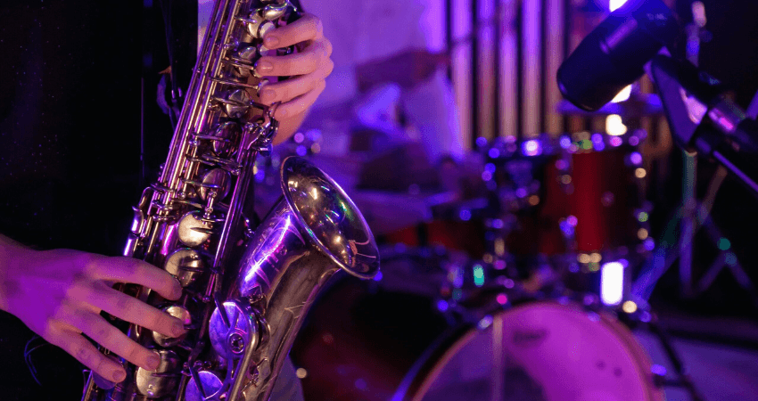A close of up photo showing a saxophone with hands playing it.