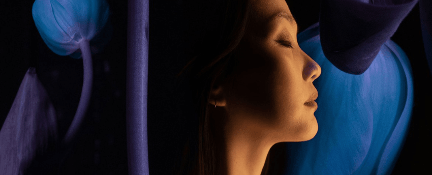 Image of a woman with her eyes closed. She is listening and there is a swirl of colours behind her.