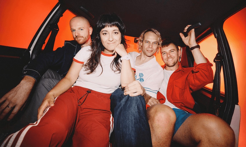 The Beths in the backseat of a car against an orange background