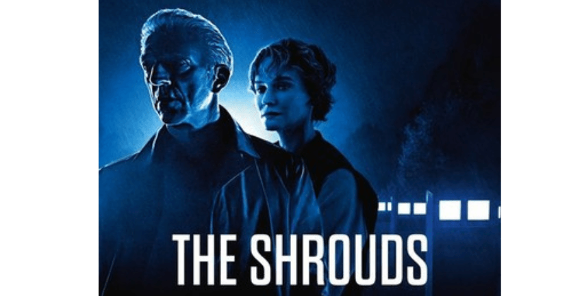 A film poster for The Shrouds which shows a man and a woman standing together looking into the distance. It is dark and there are a row of light behind them. 
