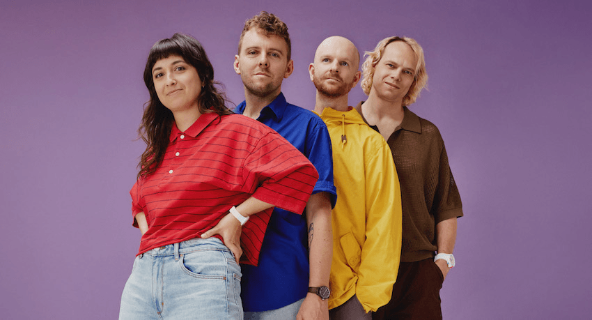 The Beths stand in primary coloured tshirts in front of a purple background