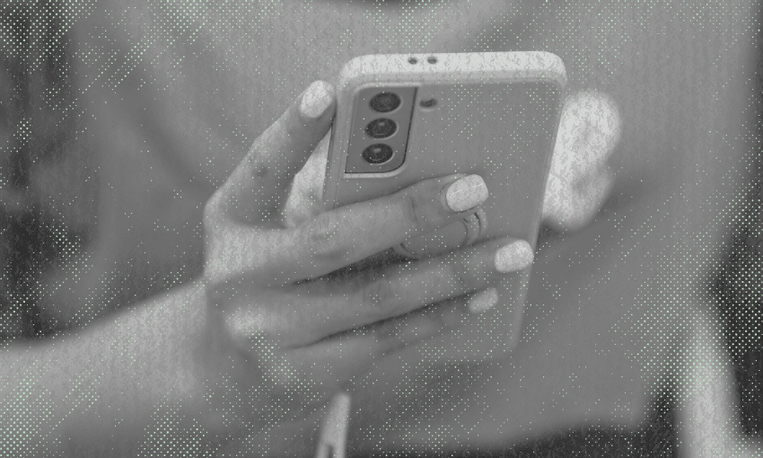 A person with manicured nails holds a smartphone with three rear cameras, using both hands. The image is in black and white with a textured, dotted overlay effect.