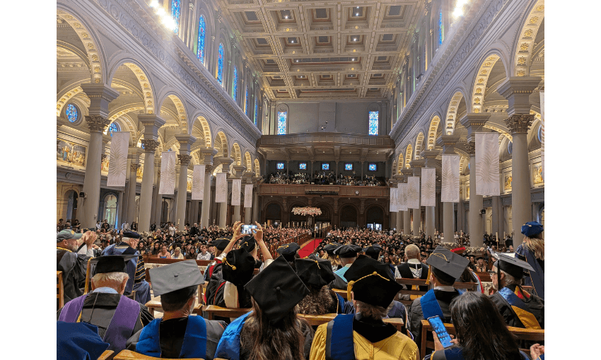 A grand building is filled with graduates for a ceremony. 
