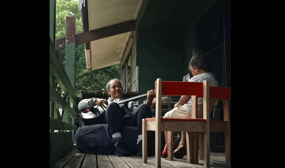 a woman sits on a beanbag playing guitar across from a small child on a wooden chair