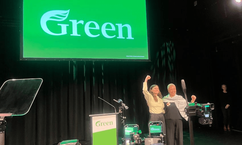 Chloe Swarbrick and Marama Davidson hold each other while waving to the crowd at the Greens' AGM.