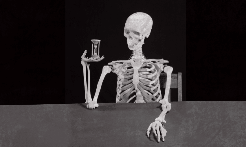 A human skeleton sits at a table, holding an hourglass in one hand and resting its other arm on the table, against a dark background.