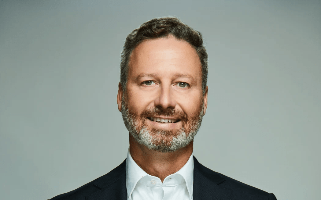 a man with a beard and short hair smiles at the camera