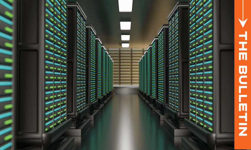 A row of server racks with glowing green and blue lights lines a hallway in a data center; "THE BULLETIN" is written vertically on an orange banner on the right side.