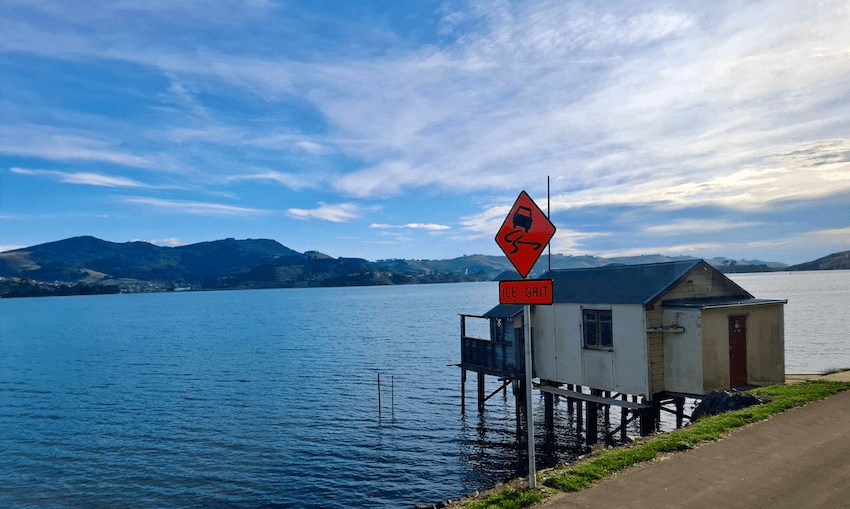 A boat shed on the Otago peninsula, with an orange sign saying "ice/grit" next to it