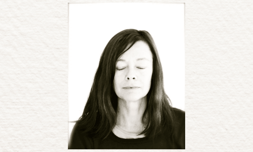 A black and white photo of Kelly Ana Morey who has her eyes closed and has long dark hair. 