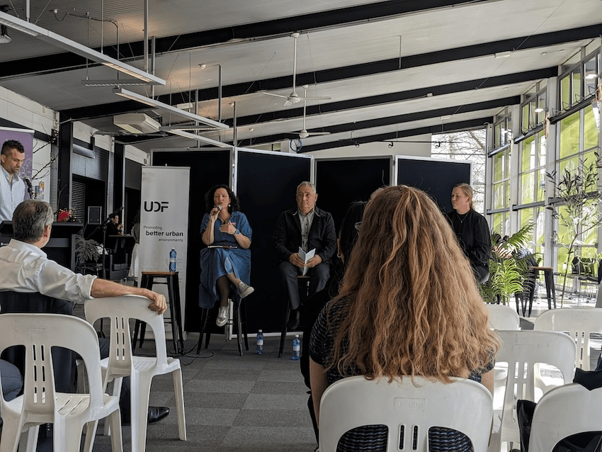 a slightly blurry photo of two people ina grey-events room, onean middleaged man and one a middle aged woman