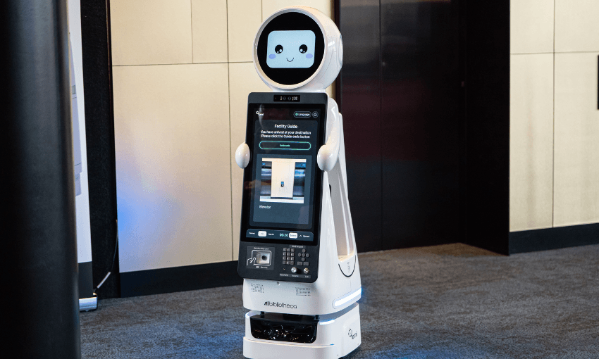 A photo of a robot with a smiley face and buttons on its front. It's frame is smooth and white.