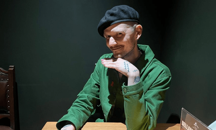 Benjamin Doyle, dressed in green, poses with their chin on their hand in parliament's Pint of Order bar.