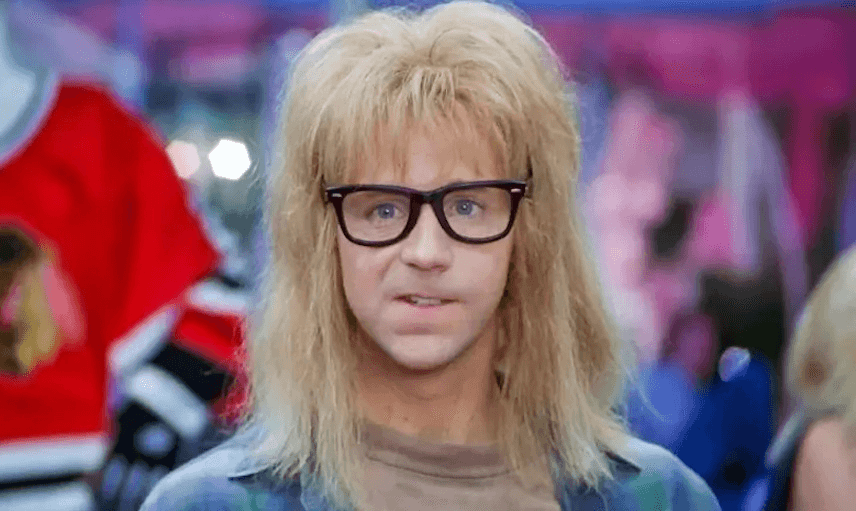A man with a fluffy blonde mullet and glasses stares nervously at the camera