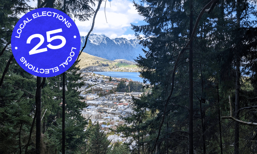 pine trees framing houses in central queenstown and the shining blue lake
