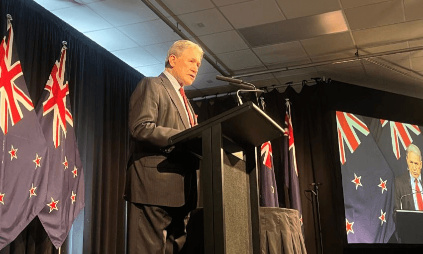 Winston Peters speaks in front of a podium.