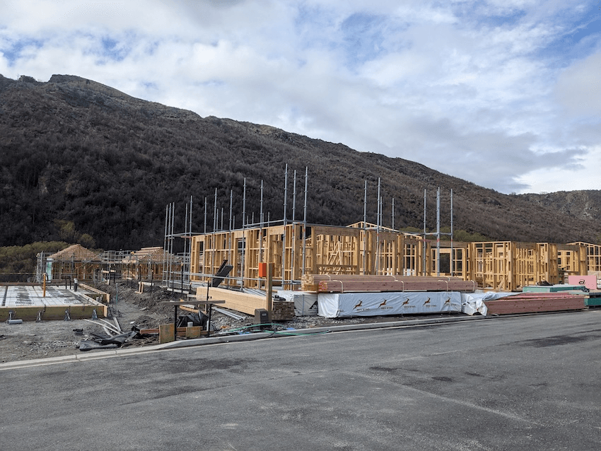a building site with lots of timber frame houses and some hills in the background