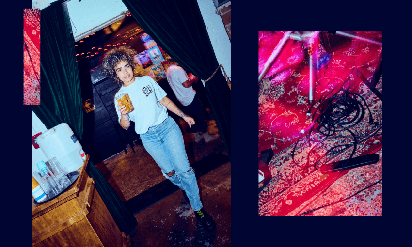 A person with curly hair, wearing a white t-shirt and ripped jeans, holds a drink while walking through dark green curtains. Beside them, a photo shows tangled cables on a red patterned rug.