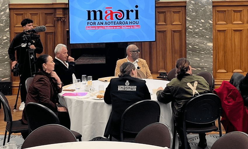 A table under a Te Pāti Māori sign occupied by Rawiri Waititi, Debbie Ngarewa-Packer, John Tamihere and two women.