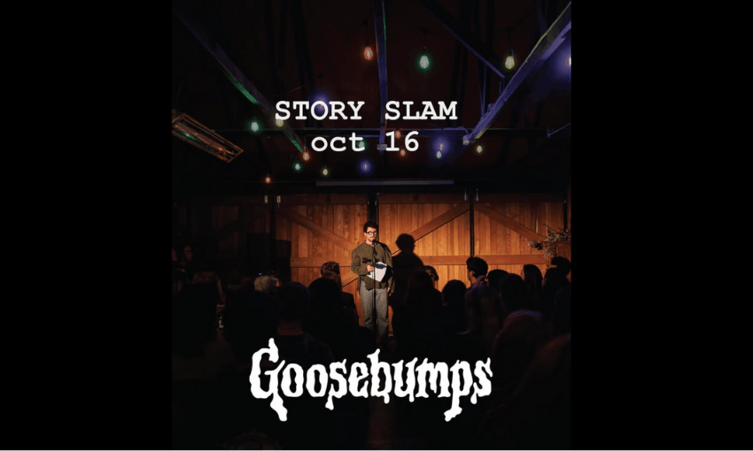 A man is standing on a stage which has one mic on a stand. He is reading from a piece of paper. The room is dark but looks full. There are words on top including the word 'Goosebumps' in the same font as the popular book series. 