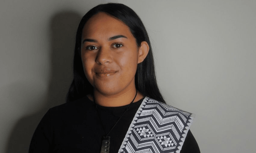A young wāhine Māori smiles against a plain background.
