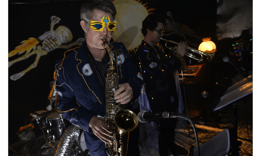 A photo of a man playing a saxophone and wearing a mask.