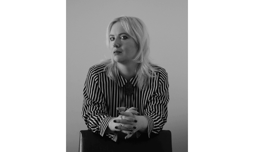 A black and white photo of a young woman with blond hair and wearing a striped shirt.