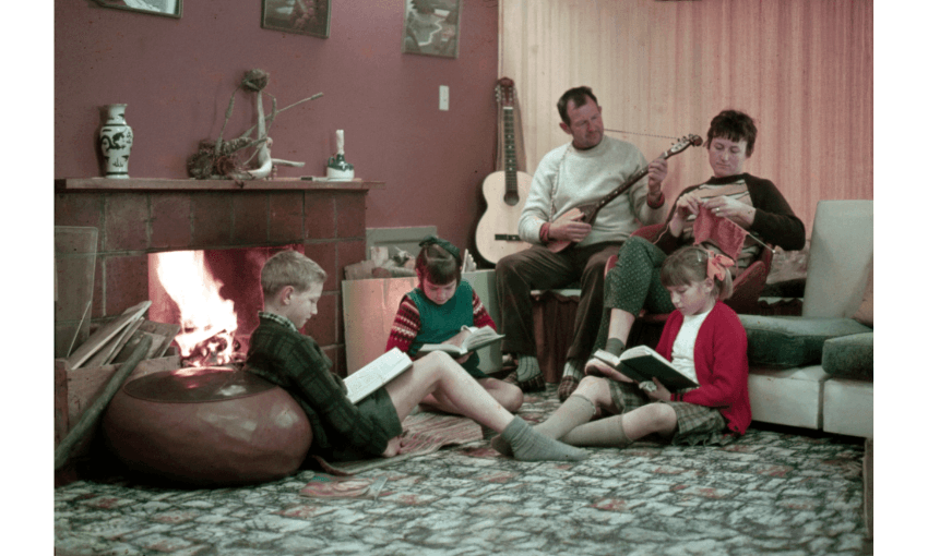 An old photo of a family sitting by a fire reading or playing an instrument or knitting.