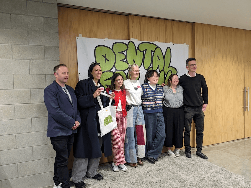 people standing in front of a banner reading Dental For all, smiling 