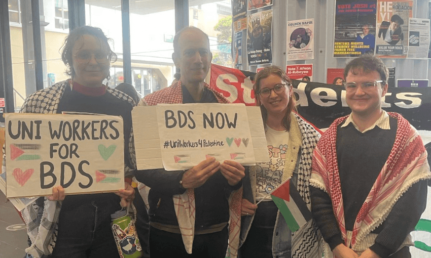 three people holding signs saying BDs, wearing kuffiyah