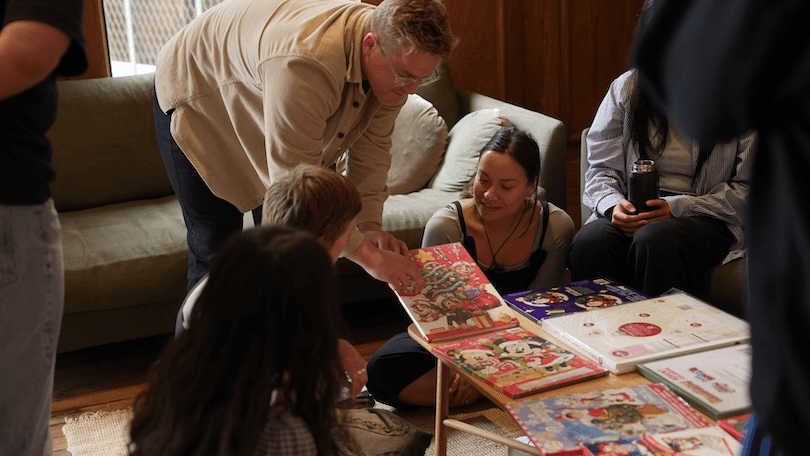 A group of people gathered around advent calendars spread out on a table.