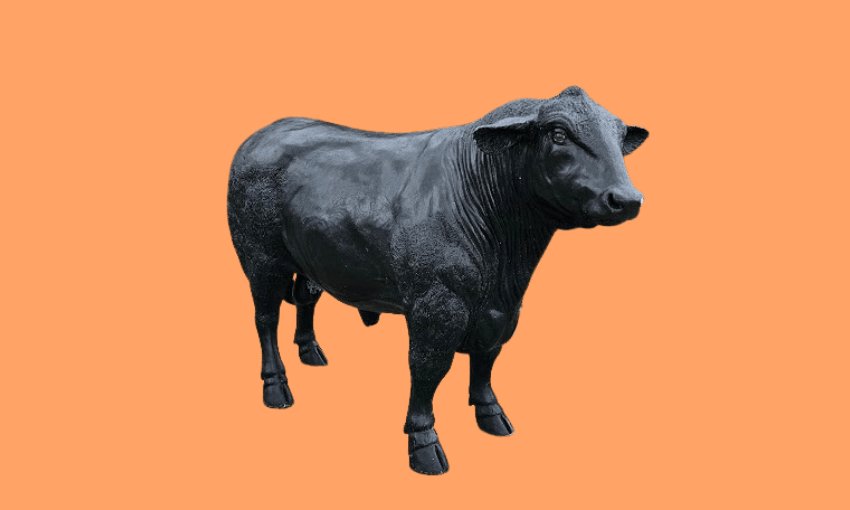 A black statue of a bull stands on an orange background, facing slightly to the right. The sculpture captures realistic muscular details and textures.