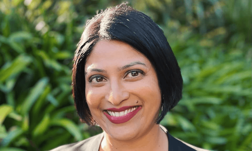Headshot of Priyanca Radhakrishnan, standing in front of greenery.