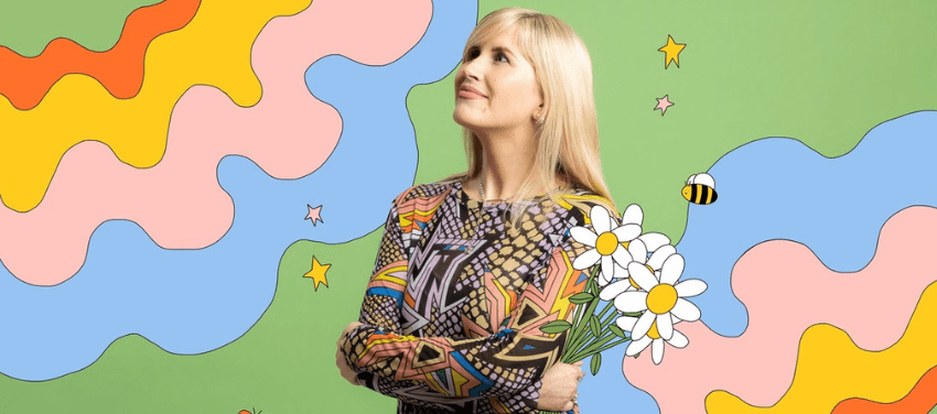 A photo of artist Ruby Jones who is a young woman with blonde hair. She is holding flowers and behind her is a swirly colourful background.