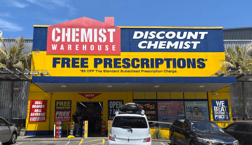 A bright yellow Chemist Warehouse against a blue Auckland sky