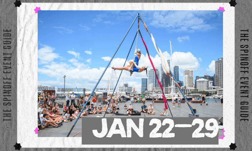 A photograph of circus performers set up outside on a waterfront space with a crowd watching.