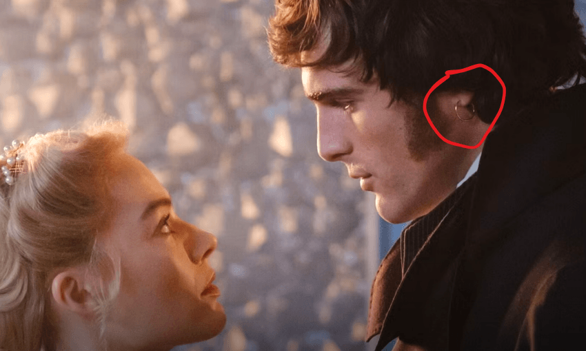 A close up shot of Margot Robbie and Jacob Elordi in Wuthering Heights. They're facing each other and a red circle highlights the gold earring in Elordi's ear.