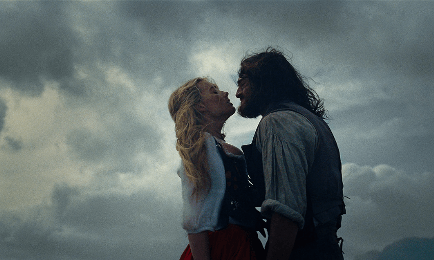 Margot Robbie and Jacob Elordi in Wuthering Heights. They are close together with the moody sky behind them.