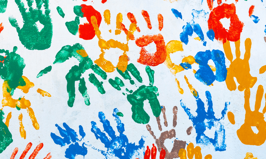 A photograph of a piece of white material covered in hand prints of bright paint.