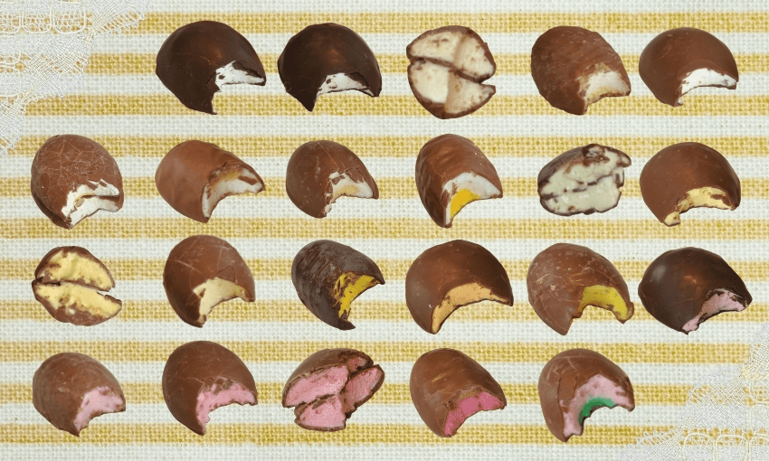 Rows of chocolate-covered sweets, each cut in half to show colorful fillings in shades of white, yellow, green, pink, and brown, arranged neatly on a striped yellow and white background.