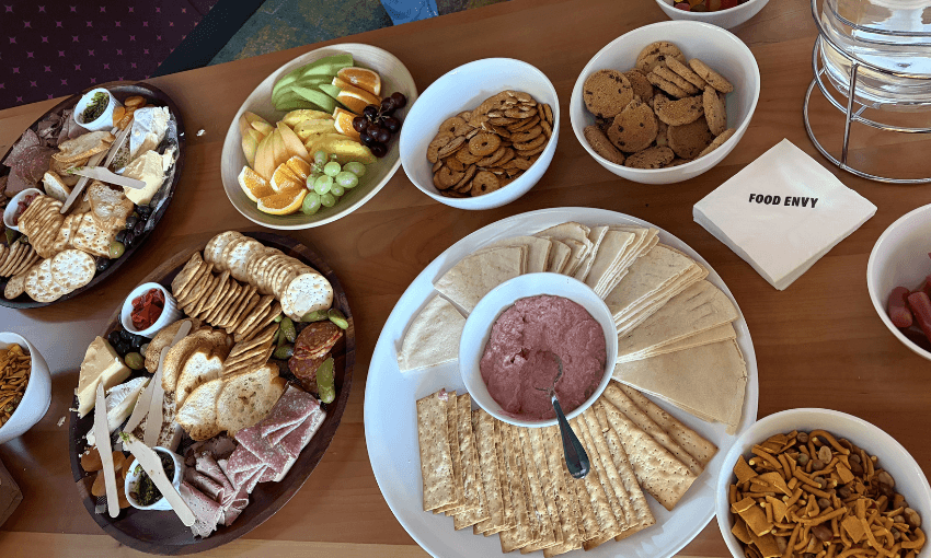 A table covered in snack plates: cheese platters, lolly bowls and fruit.