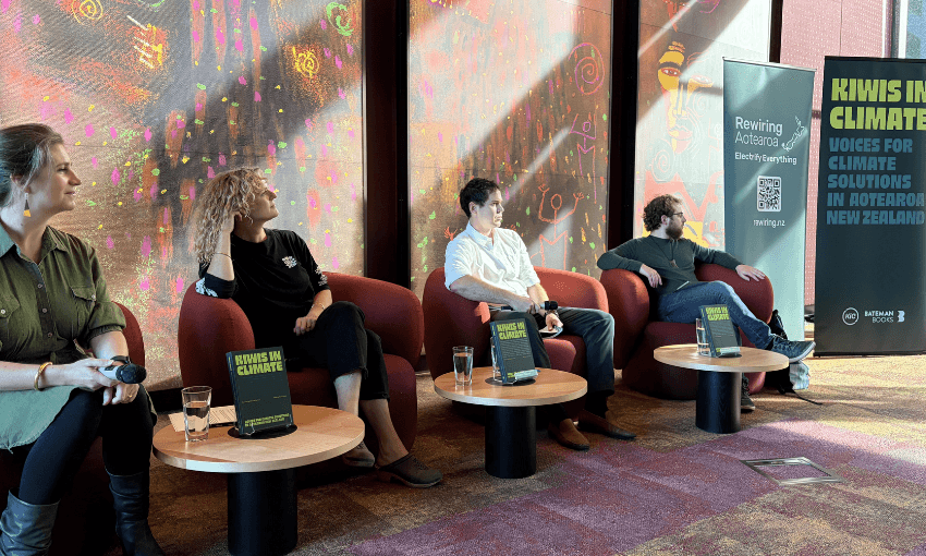 Four people are seated in armchairs each with a little table in front with a book, Kiwis in Climate, and a glass of water. They are panel speakers in an event on climate communication. They are in a beautiful room with painted walls.