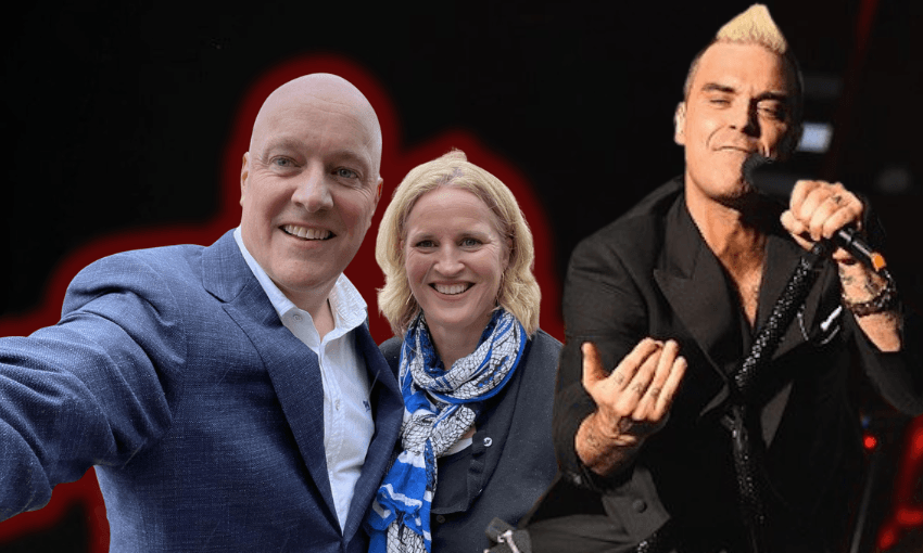 A man and woman smiling and posing for a selfie, both dressed formally, with a male singer in black performing passionately with a microphone beside them, all set against a dark background.