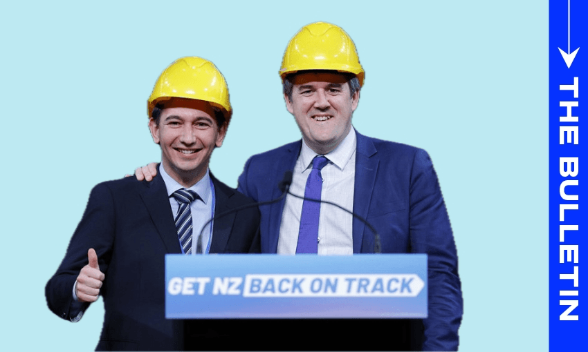 Two men in suits and yellow construction helmets stand smiling behind a podium that reads "GET NZ BACK ON TRACK." One man has his arm around the other, and the man on the left gives a thumbs-up. The background is light blue.