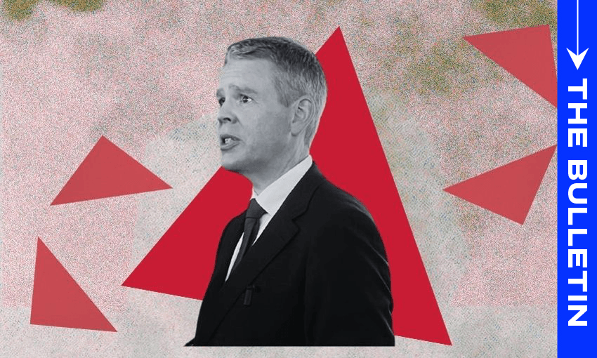 A man in a suit speaks in front of a red triangle graphic. The background is abstract with red shapes and muted colors. A blue vertical banner on the right reads "THE BULLETIN" with a white arrow above it.