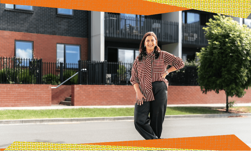 Hayley Sproull stands in front of a row of terraced townhouses, her hand on her hip