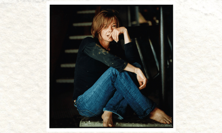 A photo of the writer Kelly Ana Morey who is wearing jeans and a black top and is sitting on the floor, her legs folded.