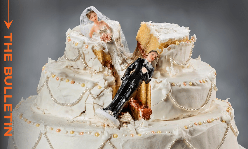 A wedding cake split down the middle with bride and groom figurines separated by the crack. The bride sits on one side, the groom lies on the other. The cake is decorated with white icing and pearls. "THE BULLETIN" is written on the left.