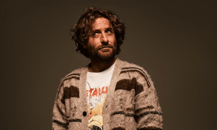 Actor Dean O'Gorman wears a brown knitted cardigan and looks upwards